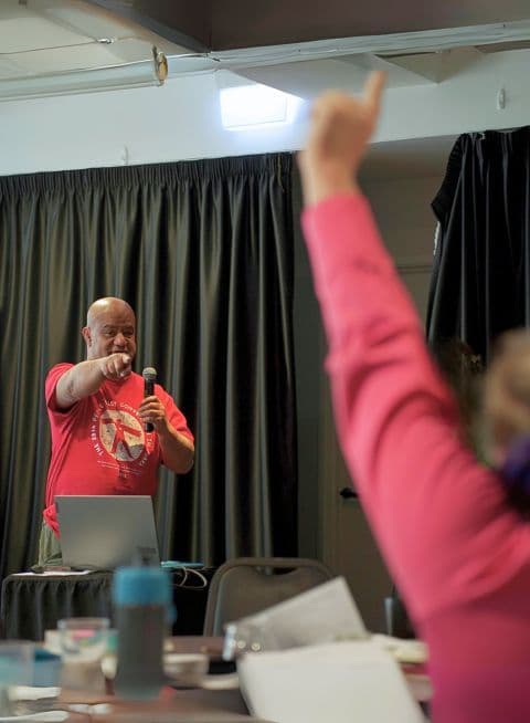 A member is pointing at someone in a pink shirt with their hand up.